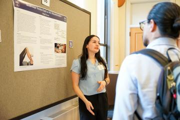 An undergraduate student discussing her poster at the 2026 STEM Colloquium