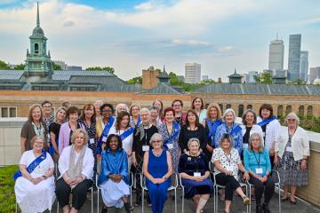 A group of Reunion attendees on the roof with Boston in the background