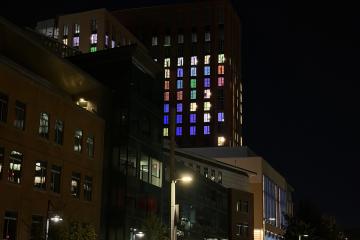 The Living and Learning Center lit up from within at night. The colors are set in the individual dorm rooms.