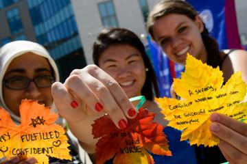 Student displaying leaves with messages of why they love Simmons