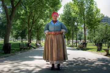 Cheyney McKnight standing in the Boston Common dressed as an enslaved woman.