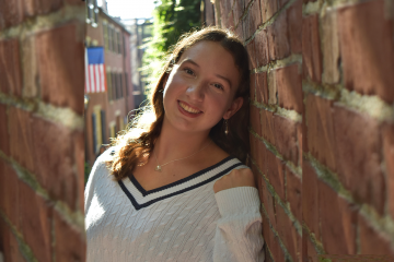 Anna Kelly leaning against a brick wall and smiling