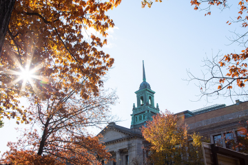 The cupola of the Main College Building on the Simmons University campus, as seen through a tree with colorful fall leaves