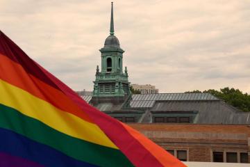 The cupola of the Main College Building on the Simmons campus with a Pride flag in the foreground