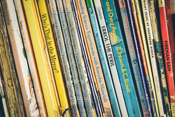 A row of children's books on a shelf. Robyn Budlender robzy_m, CC0, via Wikimedia Commons