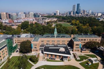 An aerial photo of the Main College Building on the Simmons campus, with the city of Boston in the background