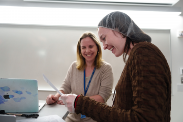 A faculty member working with a student - both are smiling as they look over a paper
