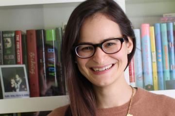 Rotem Moscovich standing in front of a shelf full of books