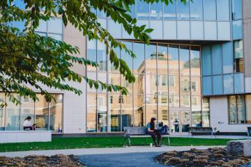 A student sits on a bench outside a building on the Simmons University campus