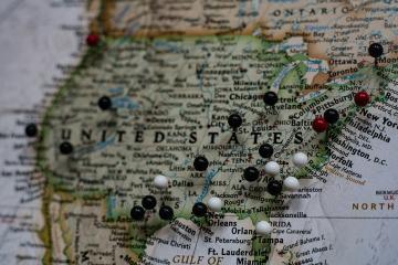 A close up of the United States on a globe with a variety of push pins marking different locations