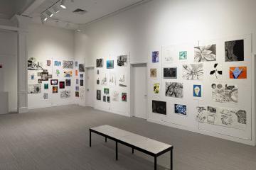 A wall in the Trustman Gallery adorned with student work