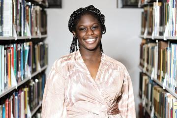 Kayla Pringle ’26 standing among the book stacks in the Simmons library