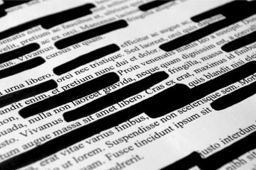 A close up photo of a block of text, much of which has been crossed out with a black marker