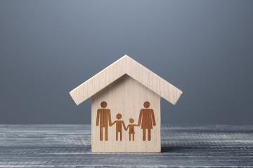A house cut out of wood with an etching of a family in the main part of the house