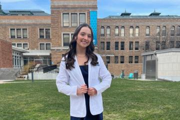 Ashley McGrath ’25 ’27DPT wearing a lab jacket on the Simmons quad