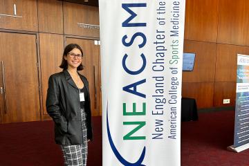 Zuzanna Misztela standing by a banner at the NEACSM Conference in 2025