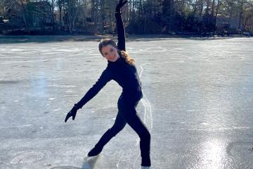 Arianna Joyce ’26, ’27MS standing in a pose on ice skates