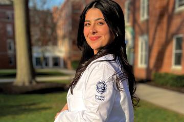 Isabella Carlos ’24DPT wearing a white coat the the Simmons logo and the words Physical Therapy on the shoulder