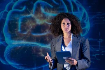 A woman making a presentation with a brain displayed on the wall behind her