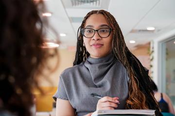 Social work student taking notes while speaking to someone