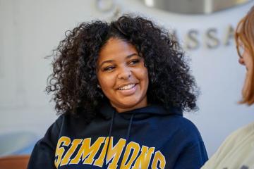 Simmons student smiling talking to another student