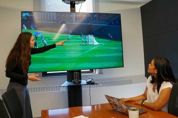 Simmons sport management student examining a lacrosse game on a monitor