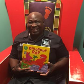 Michael Henry holding his book, Dinosaur Rap