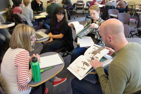 Students sitting in class looking at picture books