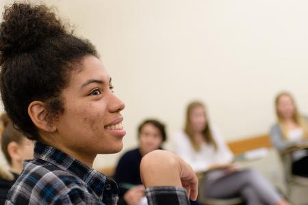 A student sitting in class with additional students sitting behind her.