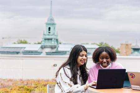 Students looking at laptop on Management Building patio