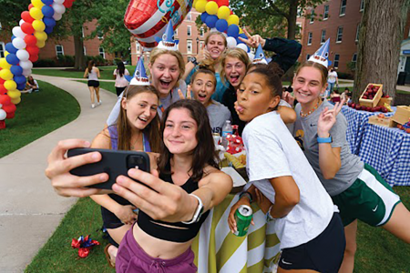 A group of Simmons students taking a selfie during an outdoor celebration.