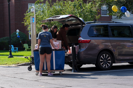 A member of the Street Team helping to unload a van full of student belongings into a cart
