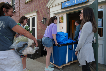 A student and family members moving belongings into a residence hall