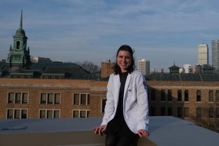 Amanda Michel ’23, ’25DPT on the Simmons campus with the Boston skyline in the background, photograph by Brad Michel