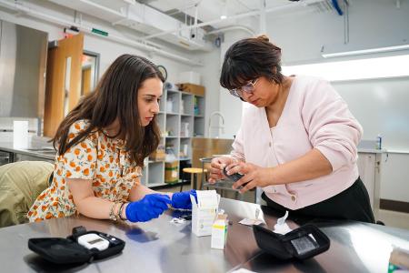 A graduate student in the nutrition lab learning how to administer a blood sugar test