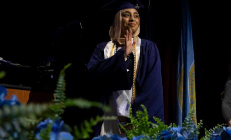 A graduating student waves as they cross the stage during Commenement 2025