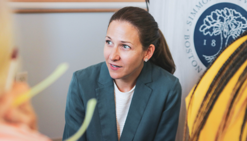 Elaine Dimopoulus wearing a green jacket and engaged in speaking