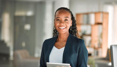 A young woman wearing a green blazer and holding a tablet 