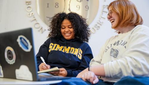 Two Simmons undergraduate students sitting near the University seal in the Main Campus Building