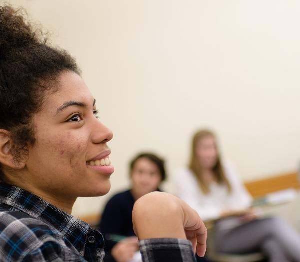 A student sitting in class with additional students sitting behind her.