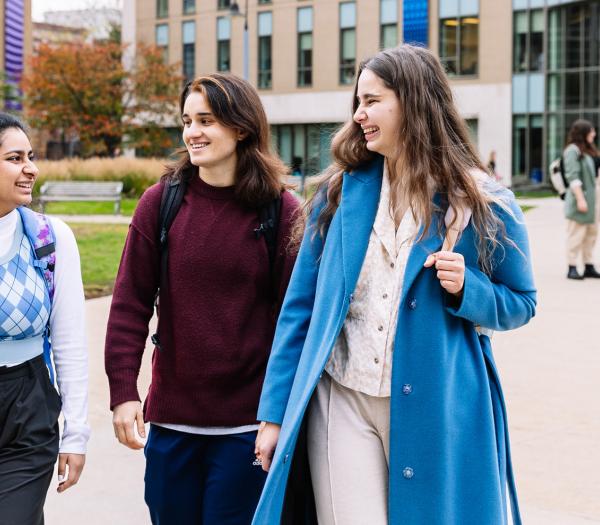Three smiling Simmons students walking together through the Main Campus Quad