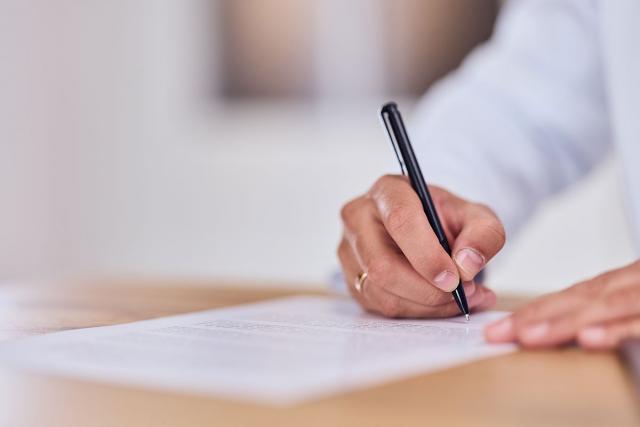 Someone signing a document with a pen