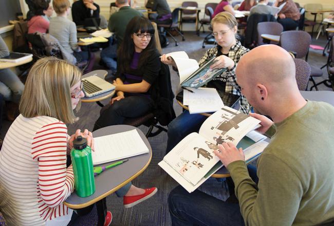 Students sitting in class looking at picture books