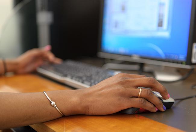 Hand using mouse at a computer. 