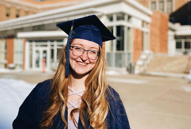 Student on campus in graduation robes