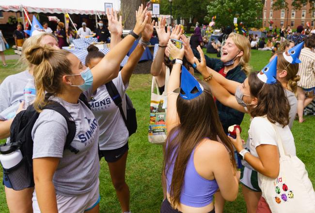 Students on Res Quad raising hands together in unity in a circle