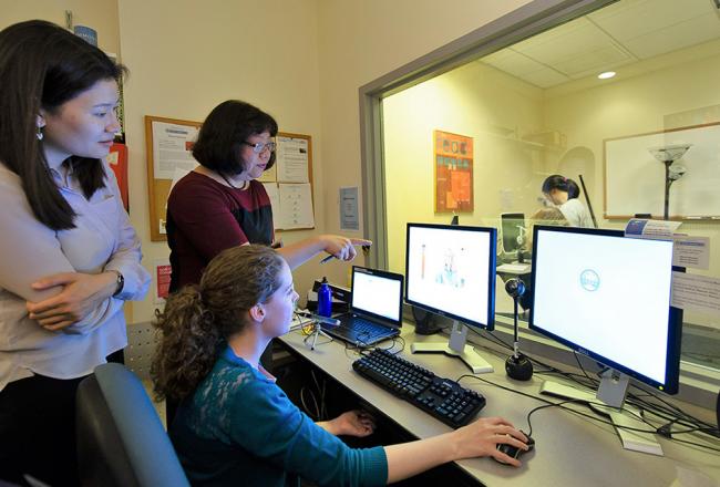 Students working on computer with professor