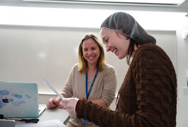 A Simmons student looking over a paper with a member of the faculty.