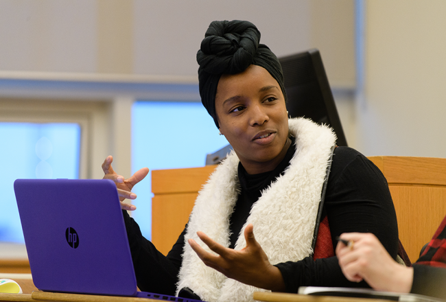 A Simmons student talking to a classmate and gesturing with their hands
