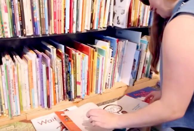 A Simmons student reading a picture book in a chidren's library